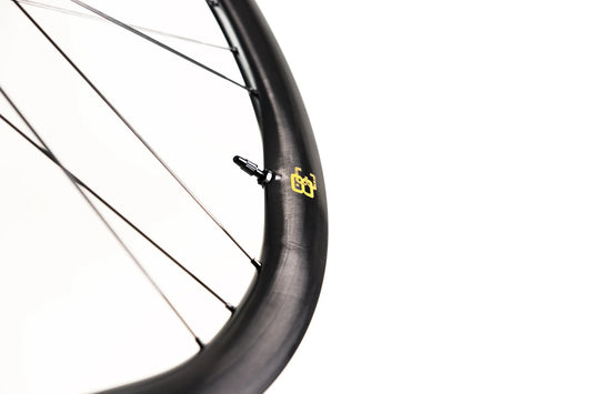 Close-up of Approved Cycling ATEM SilkRoad 3.8 wheel, detailing the innovative carbon fiber weave and tubeless valve.