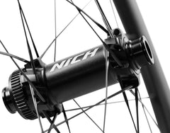 NICH Atem 4S carbon road bike wheels on a paved road, blurred background suggesting high-speed performance and efficiency.